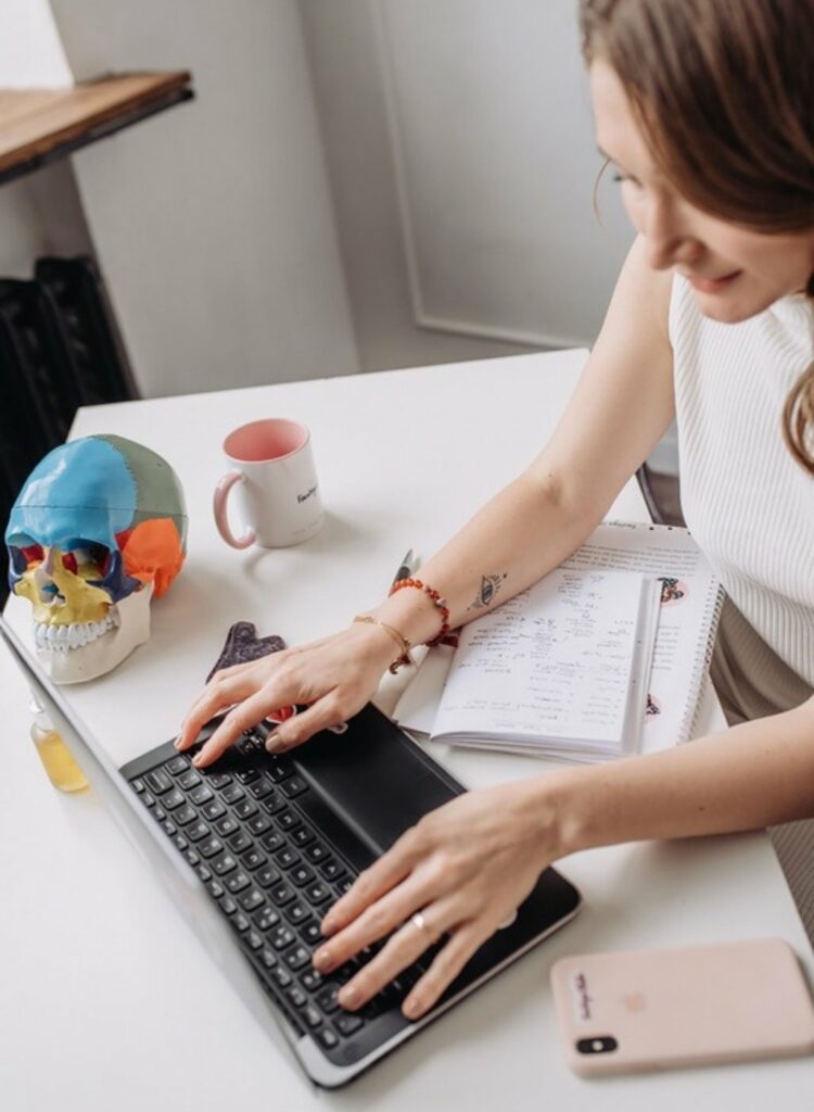 Femme qui travaille sur son ordinateur portable, carnet de notes ouvert sur le bureau