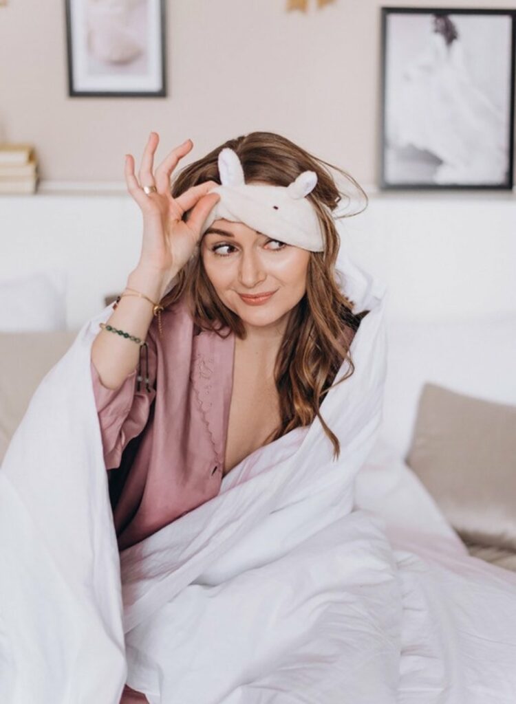 Femme au réveil dans son lit, masque de sommeil relevé sur le front